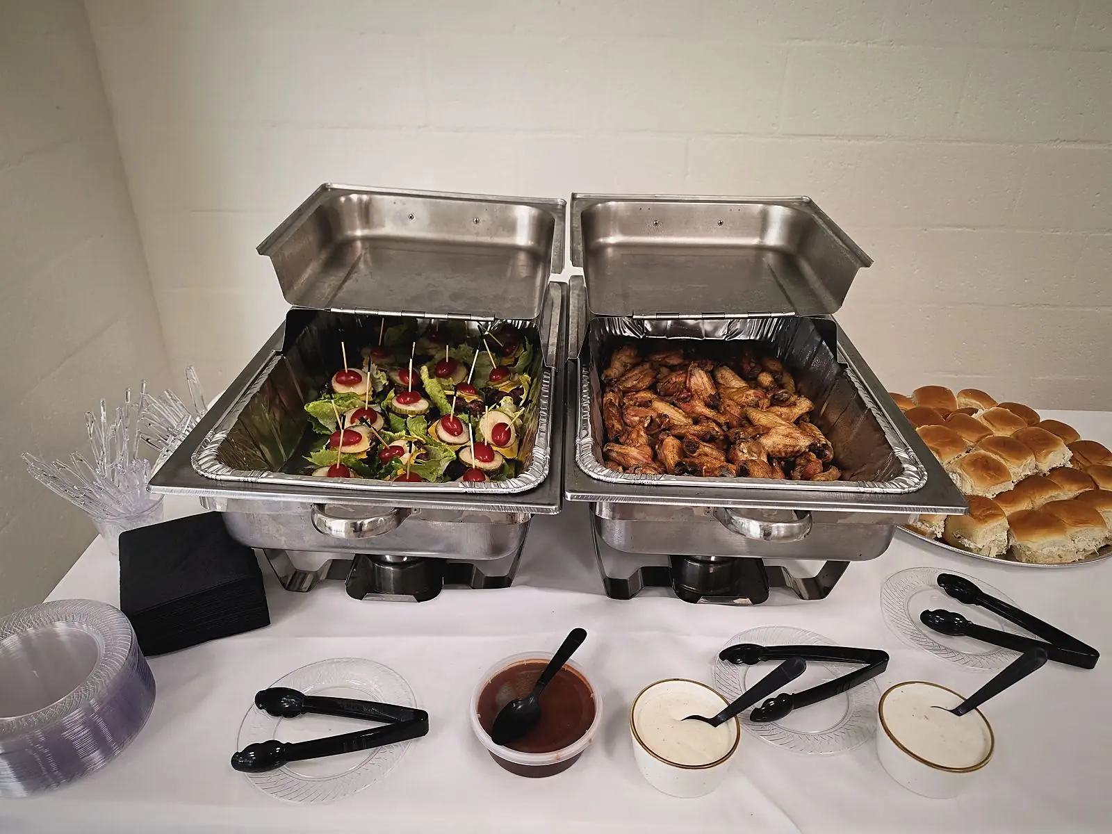 A catering spread with chafing dishes and rolls